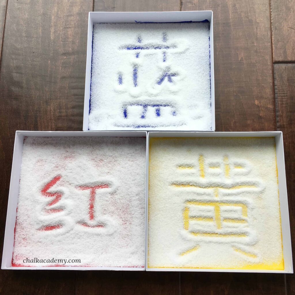 Montessori activity: colored box lids and Chinese characters written in salt