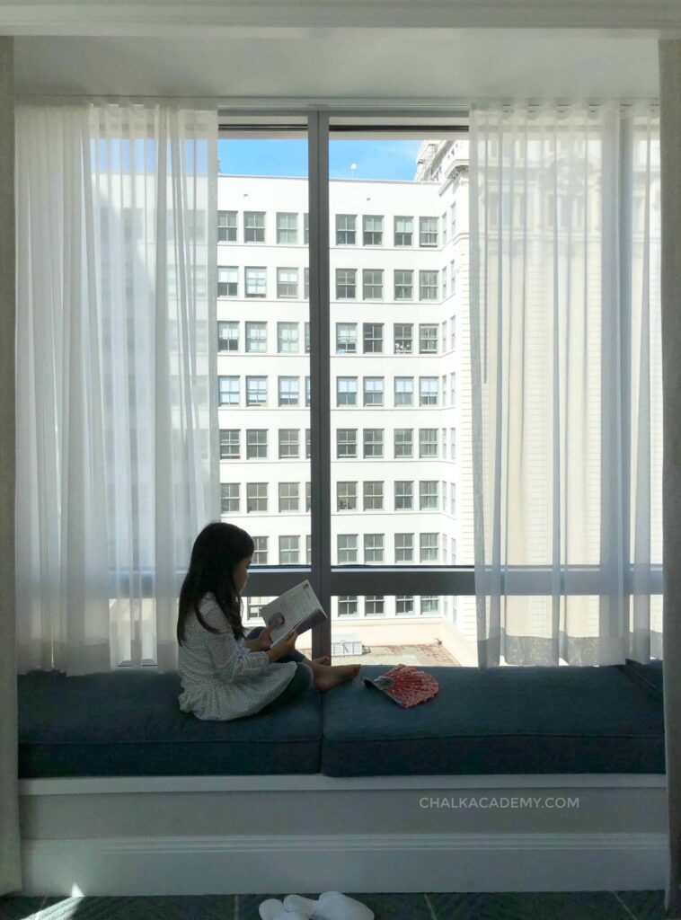  Lectura de la hija en el asiento de la ventana del hotel