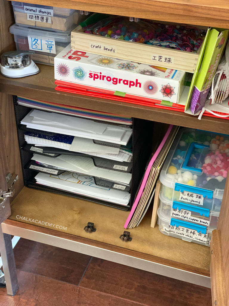 Labeled paper storage tray and craft supplies in art cabinet