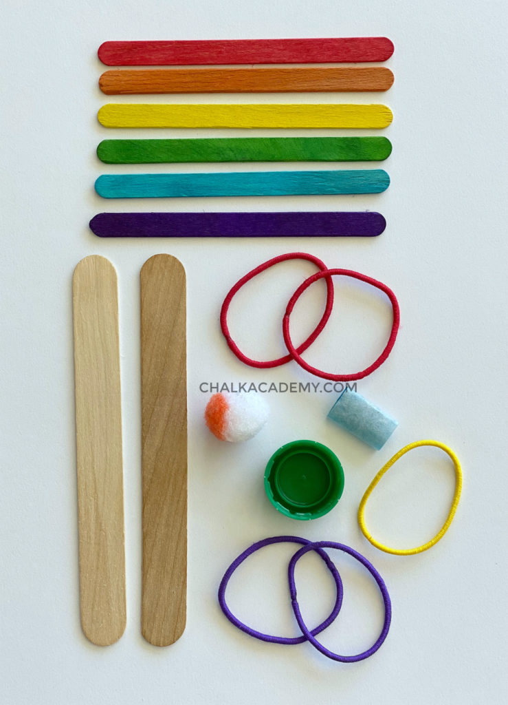 What you need to make a catapult: craft sticks, rubber bands, pom pom, bottle cap, and glue or tape