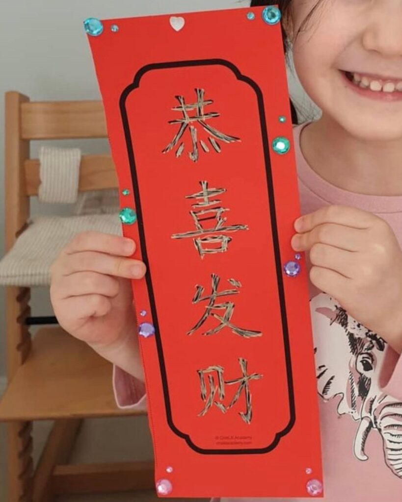 smiling child holding Chinese New Year craft
